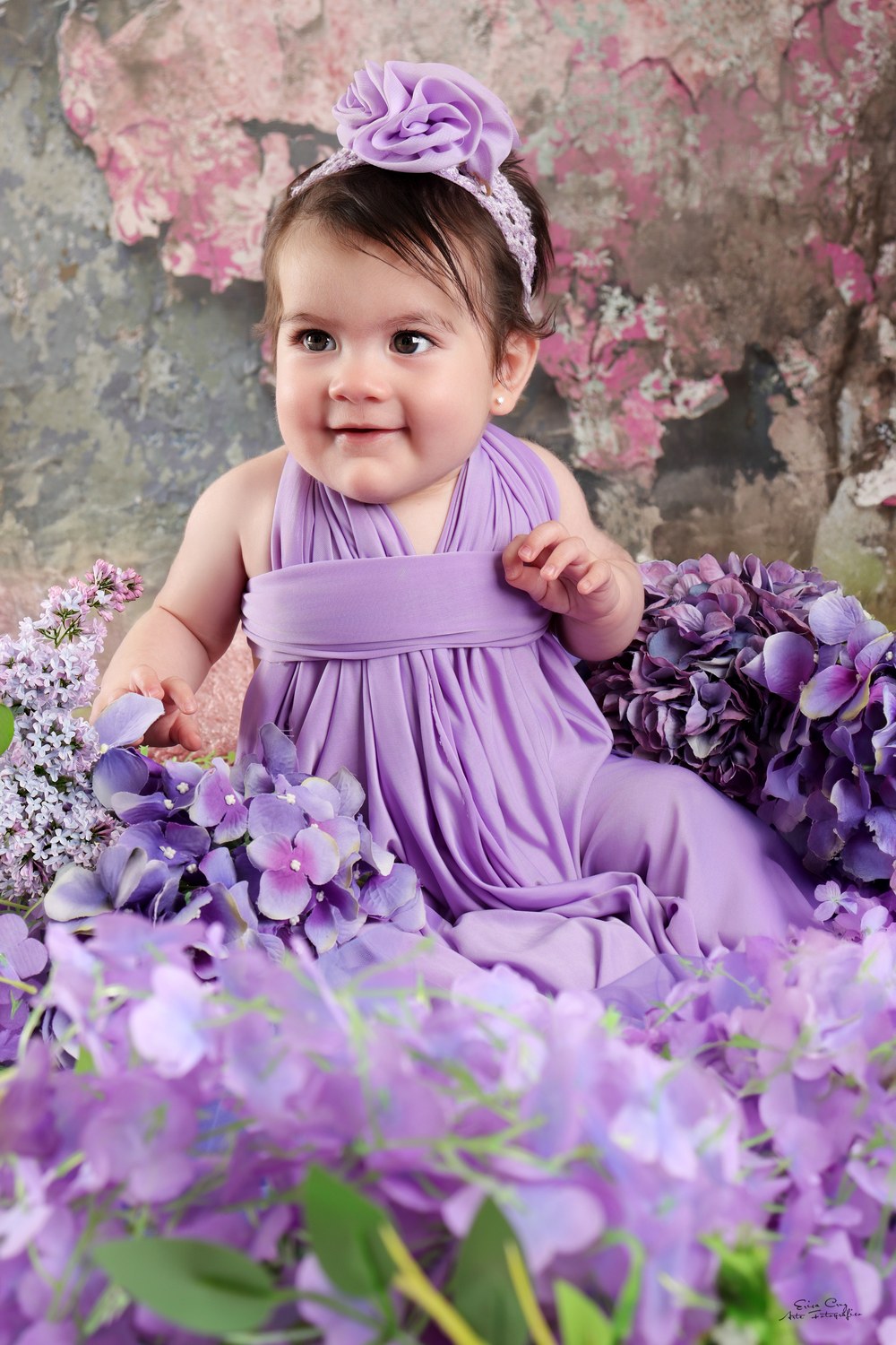 Bebé sentada entre flores moradas, Erica Cruz