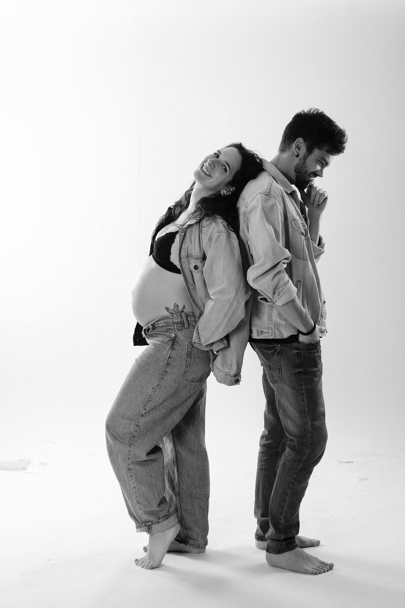 Pareja espalda con espalda riendo con chaquetas de mezclilla, blanco y negro, Erica Cruz