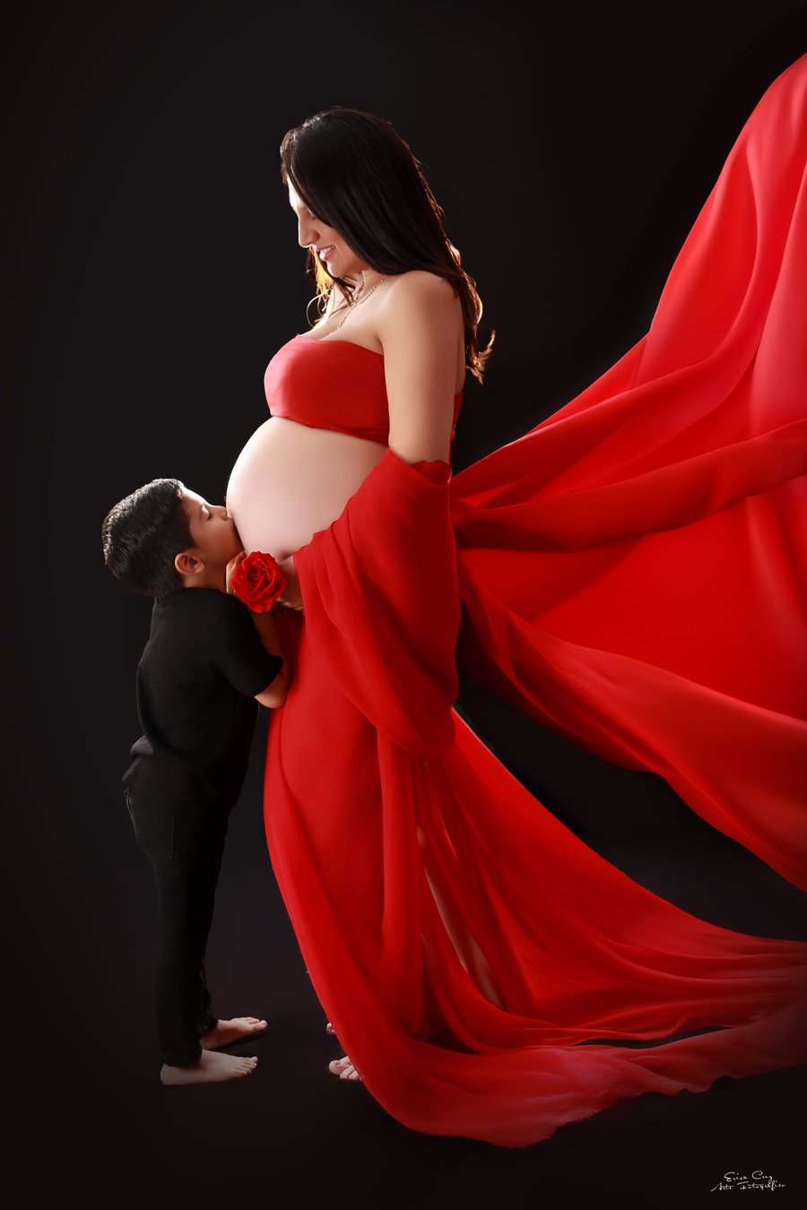 Embarazada con vestido rojo y niño besando la panza, Erica Cruz