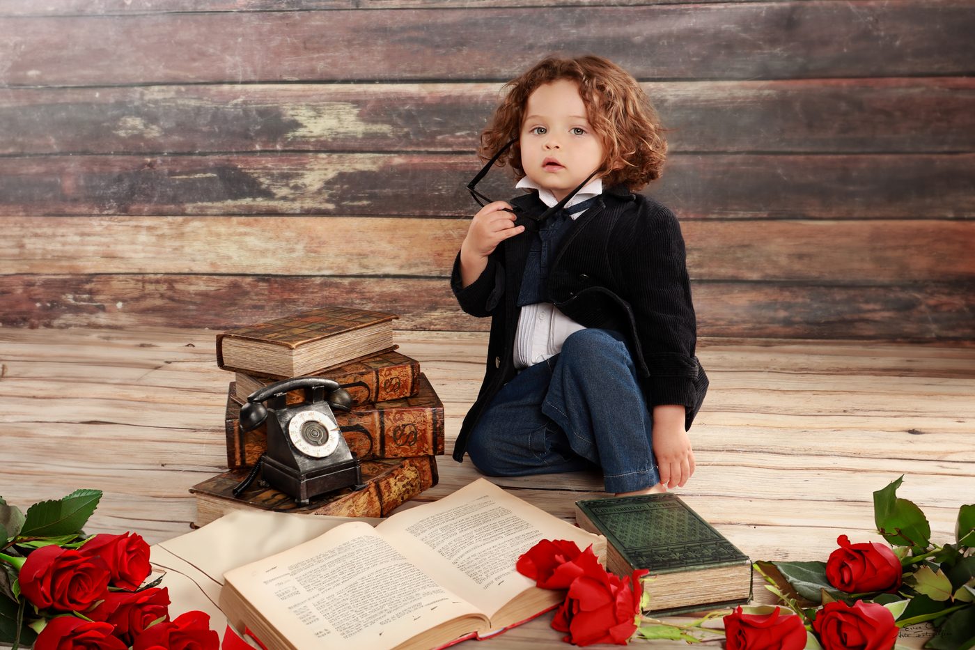 Niño con traje vintage junto a libros antiguos y rosas, Erica Cruz