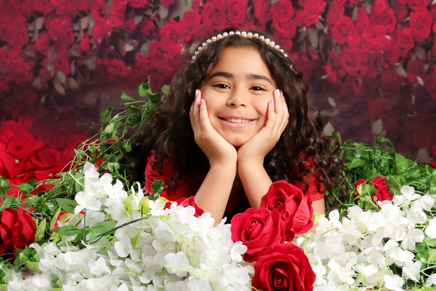 Niña con diadema de perlas entre rosas rojas, Erica Cruz