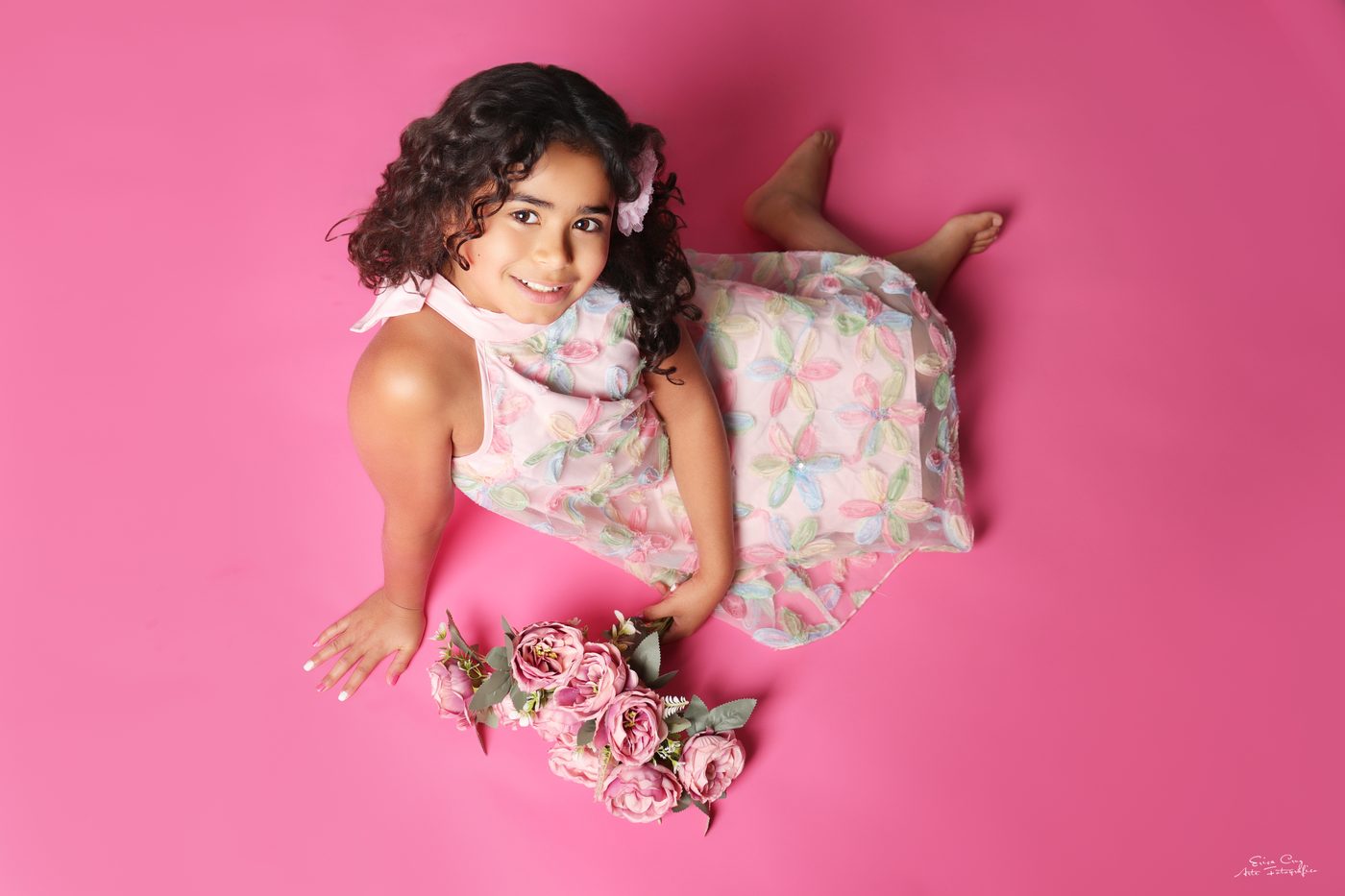 Niña con vestido floral sobre fondo rosa, Erica Cruz