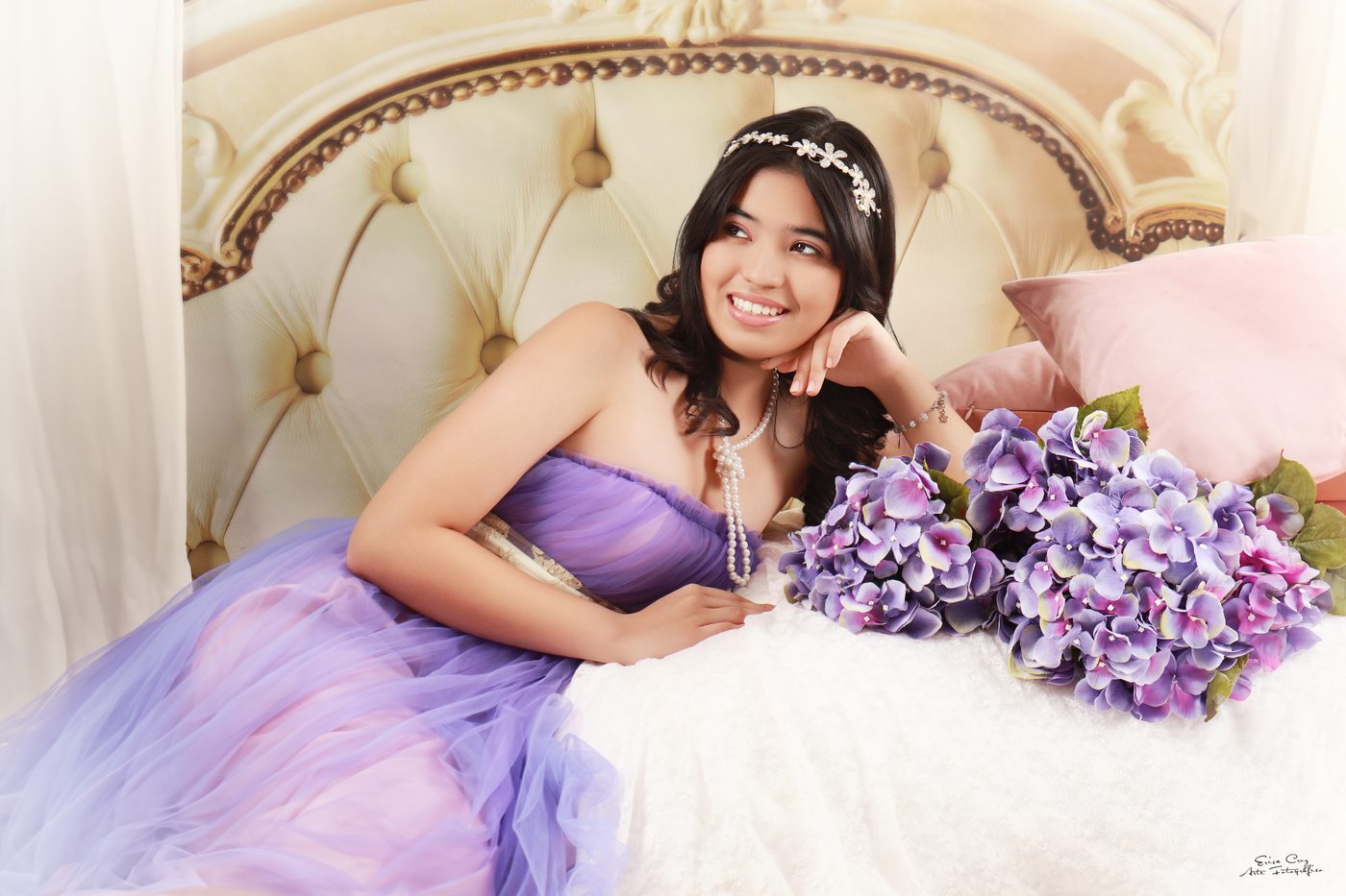 Adolescente con vestido lila recostada junto a hortensias, Erica Cruz