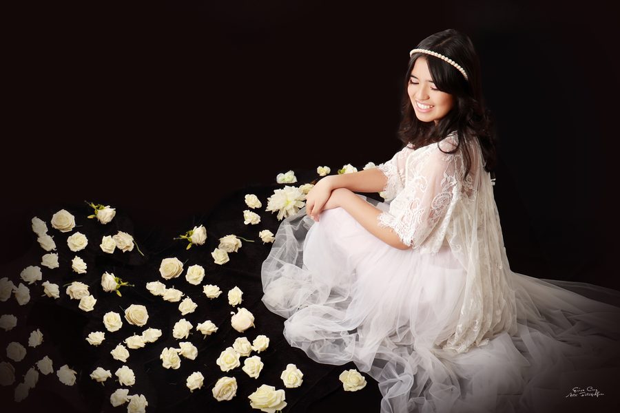 Adolescente con vestido de encaje blanco entre rosas, Erica Cruz