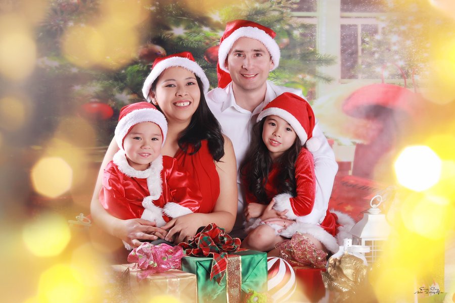 Familia con gorros navideños junto al árbol y regalos, Erica Cruz