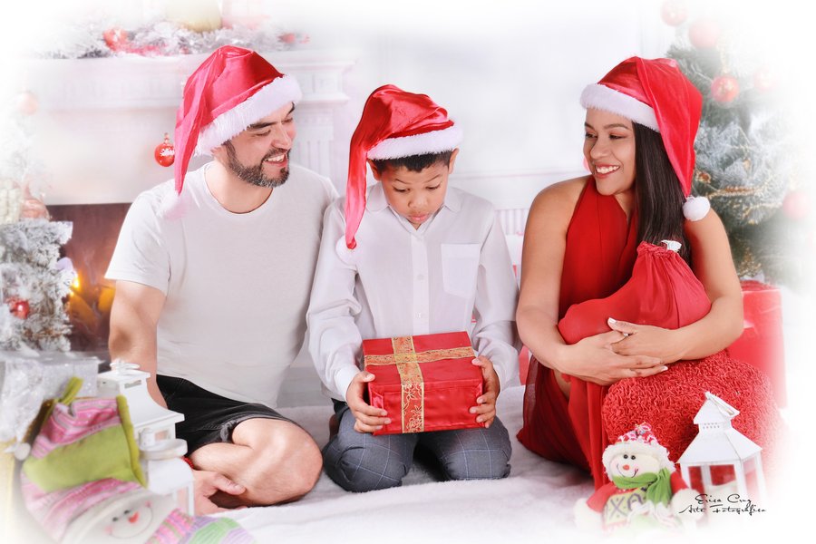 Familia abriendo regalos junto a la chimenea con gorros navideños, Erica Cruz