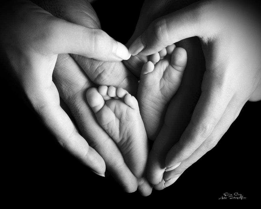 Manos de padres formando un corazón con los pies del bebé, Erica Cruz