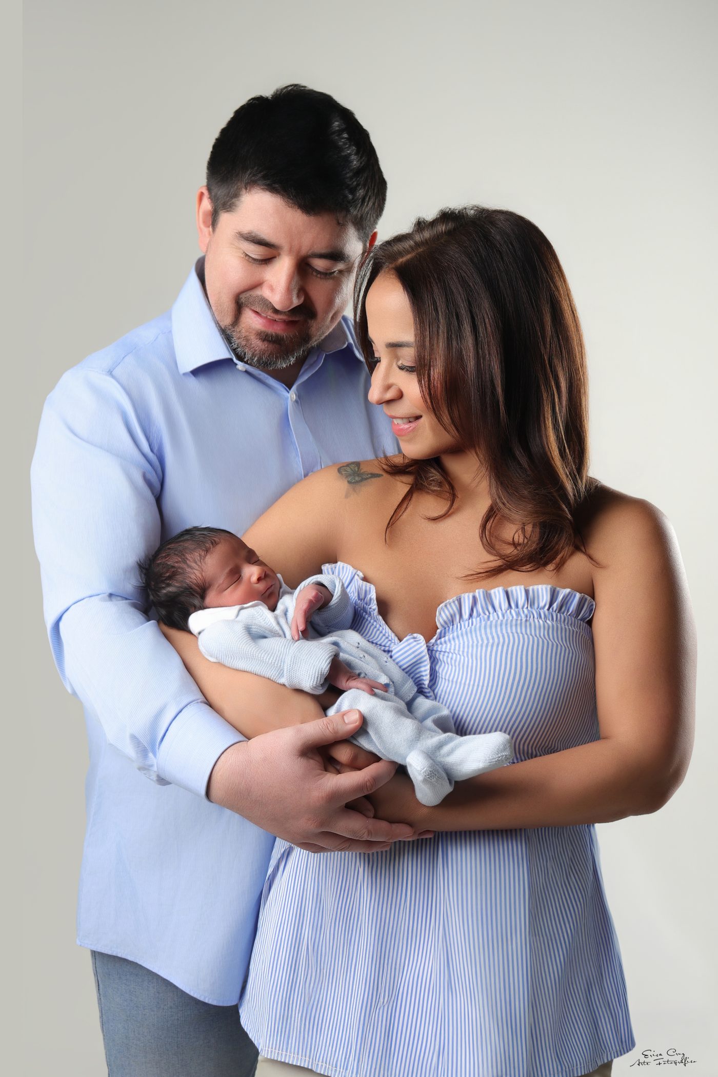 Padres sosteniendo a su recién nacido vestido de celeste, Erica Cruz